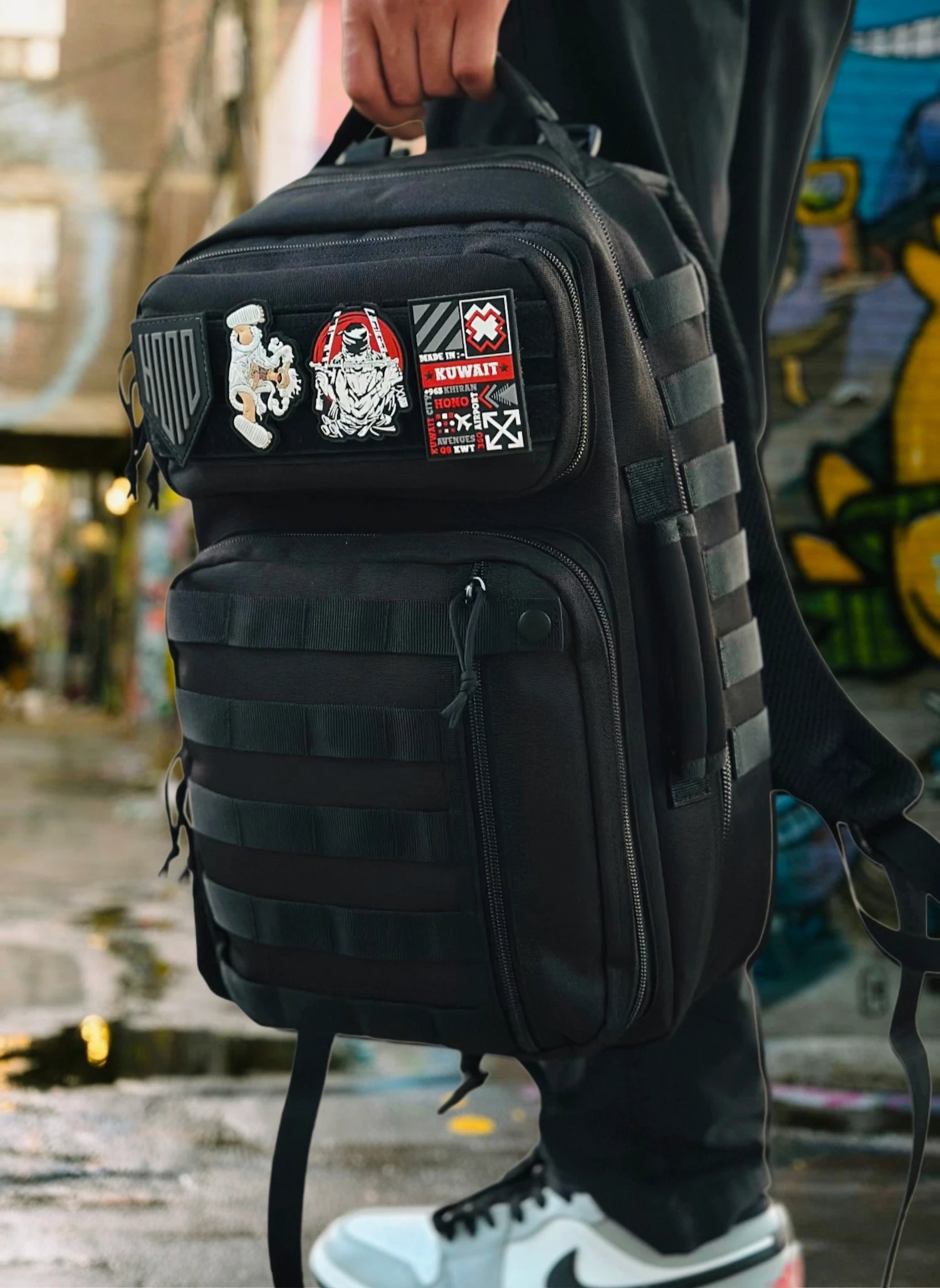 Black tactical backpack 25L with patches on a blurred street background
